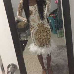 long sleeve white dress with gold details and white feathers at the bottom